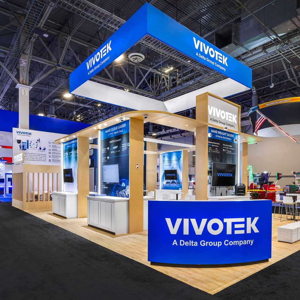 Custom vivotek trade show booth with blue overhead sign, maple wood columns, and curved reception desk at isc west